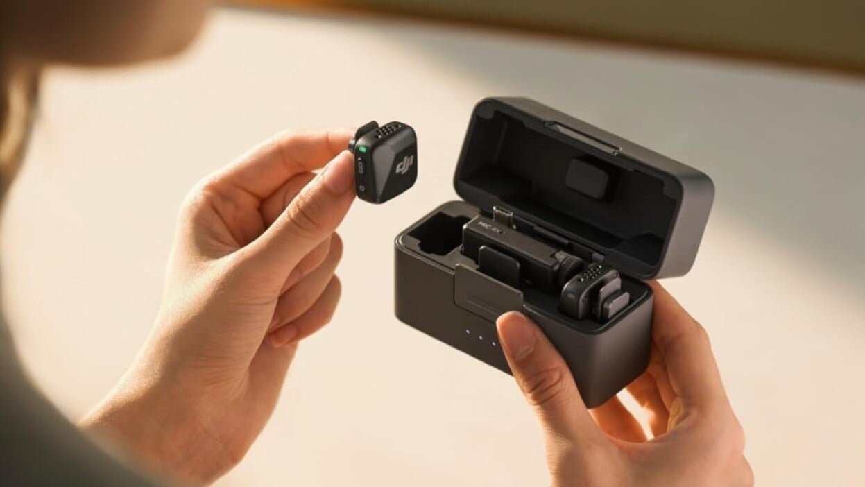 someone holds the DJI Mic mini receiver in their hand with one transceiver out of the case as we look over the person